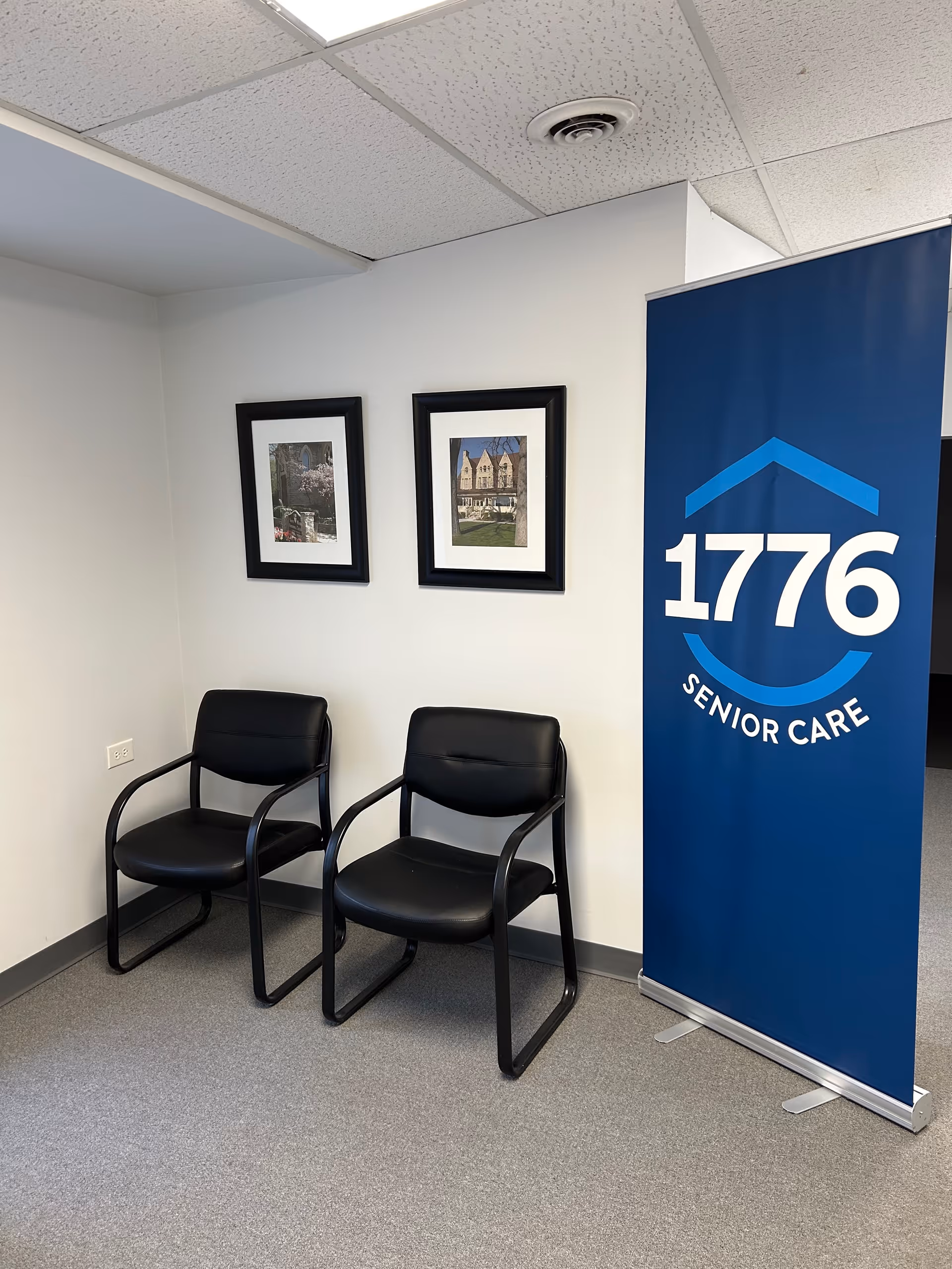 Two black chairs sit beside a blue 1776 Senior Care banner in a small lobby.