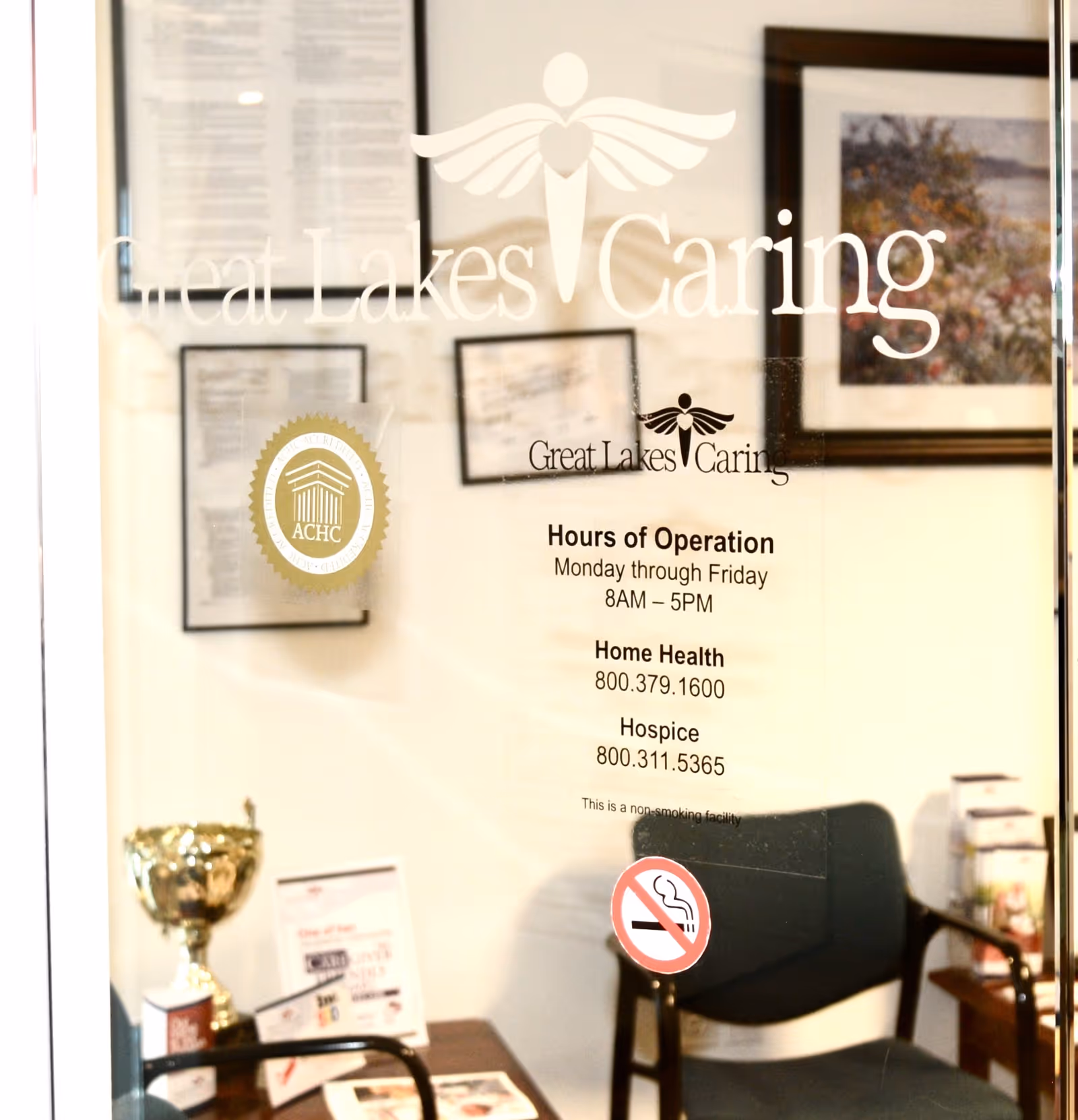 Interior lobby with glass door showing Great Lakes Caring signage and hours