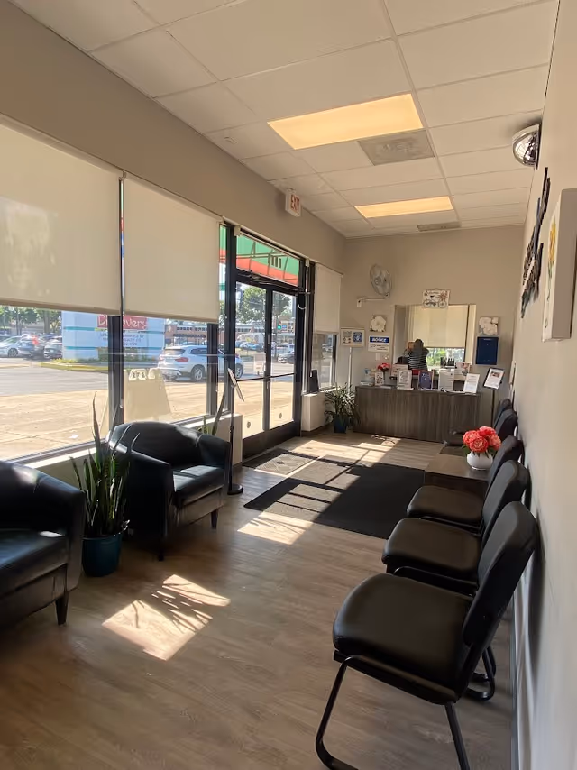 Bright facility lobby with seating, plants, large windows, and a front desk in back.