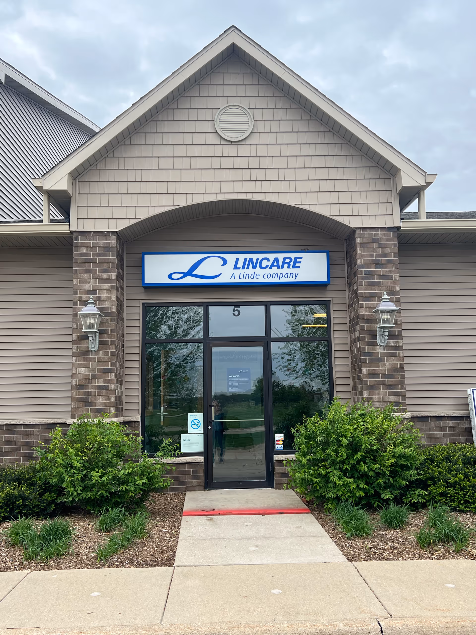 Entrance to Lincare facility with glass door, brick facade, and blue sign.