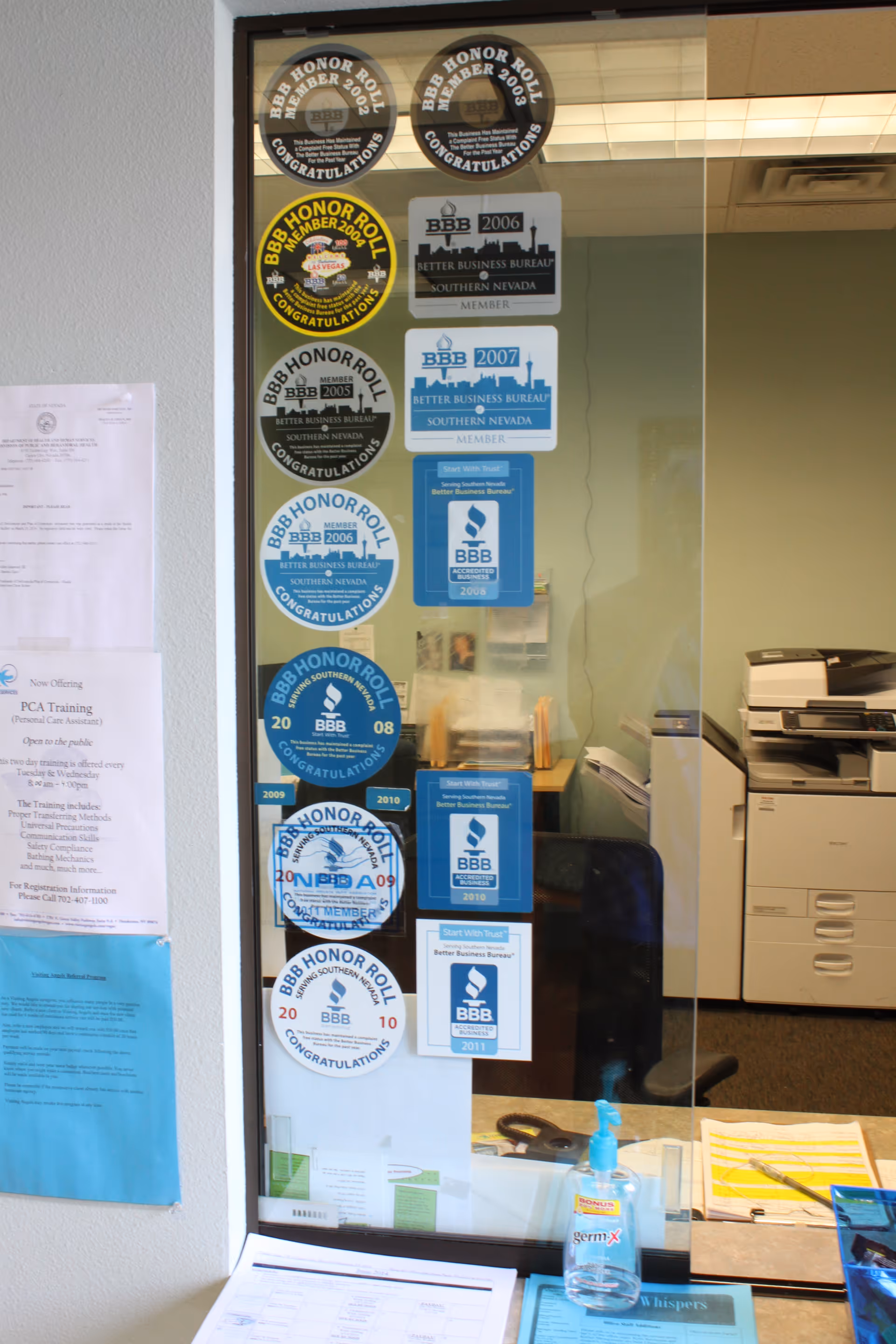 Visiting Angels office interior with BBB award stickers on glass wall.