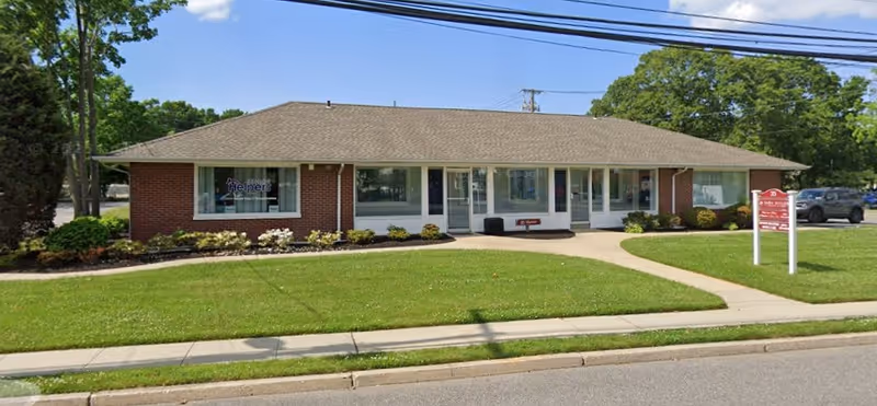 This front view shows a single-story brick Senior Helpers facility with a green lawn.