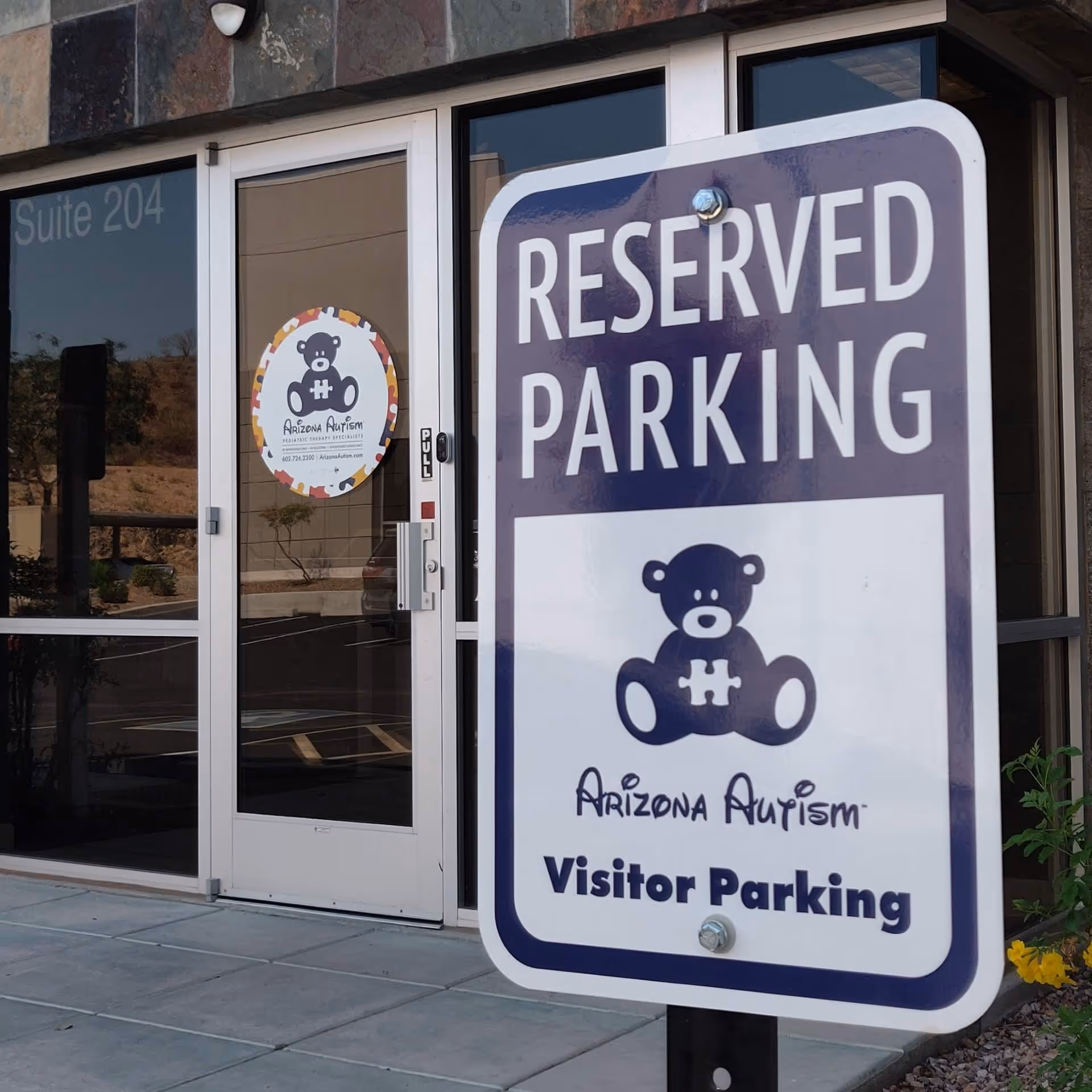 Front entrance of a building with a large Reserved Parking sign and Arizona Autism sticker.
