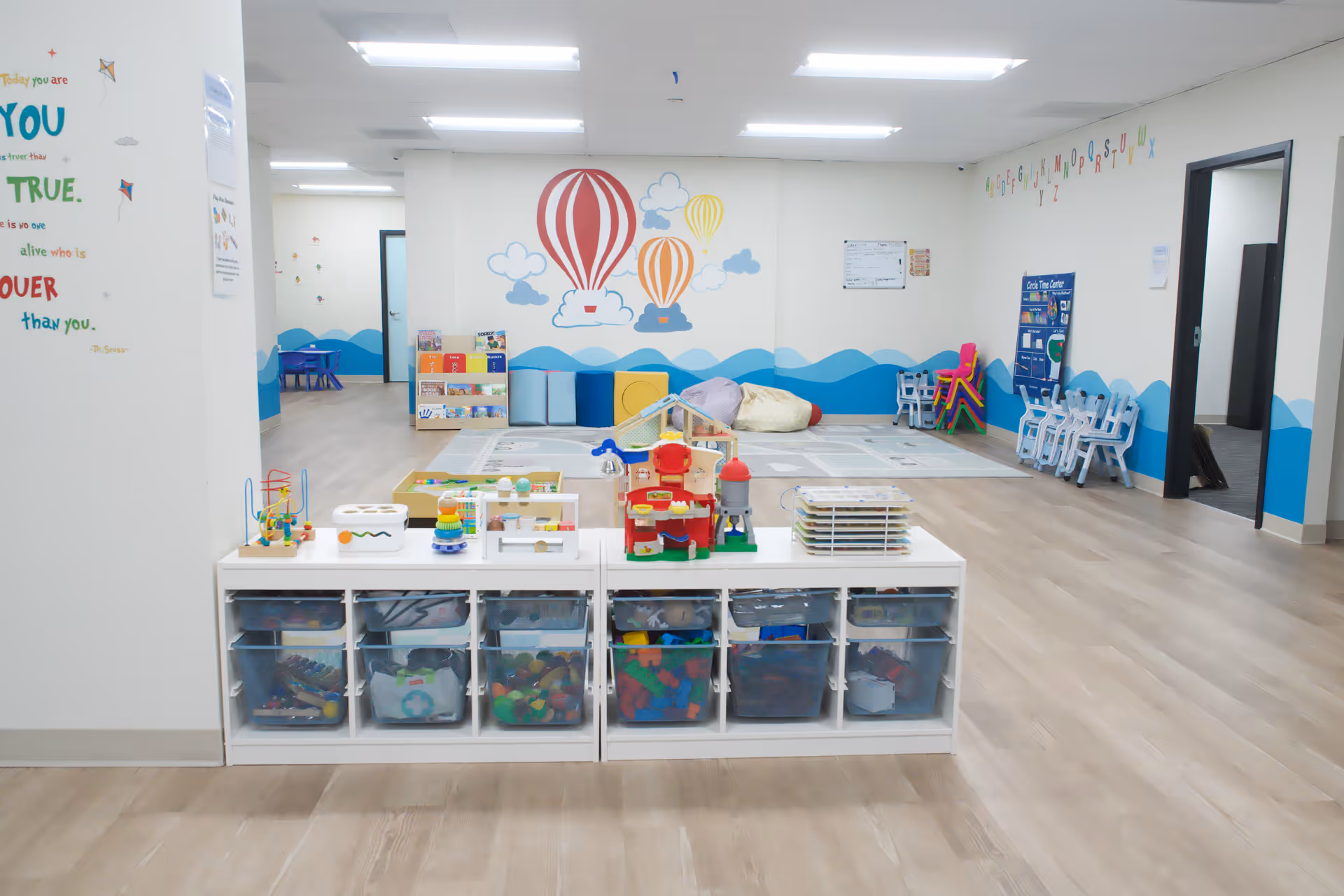 Bright children's play area in a spacious room with toys and colorful murals.