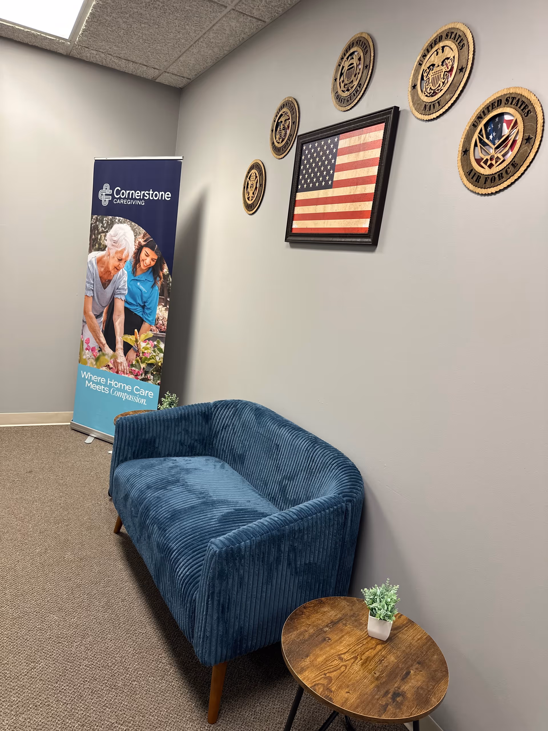 Blue curved sofa with small round table, Cornerstone banner, and American flag wall decor.