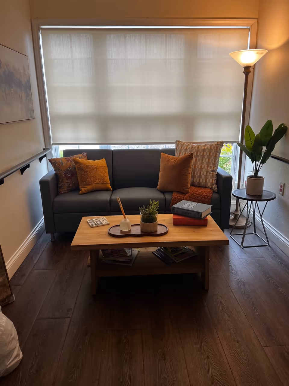 Cozy living room with a grey sofa, orange pillows, wooden coffee table, and floor lamp.