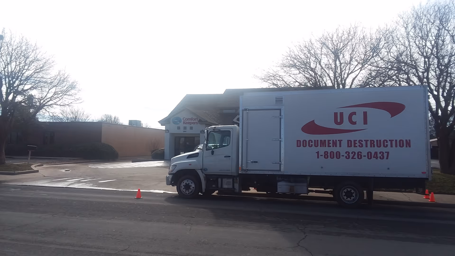 A Comfort Keepers facility front with a large UCI document destruction truck parked outside.