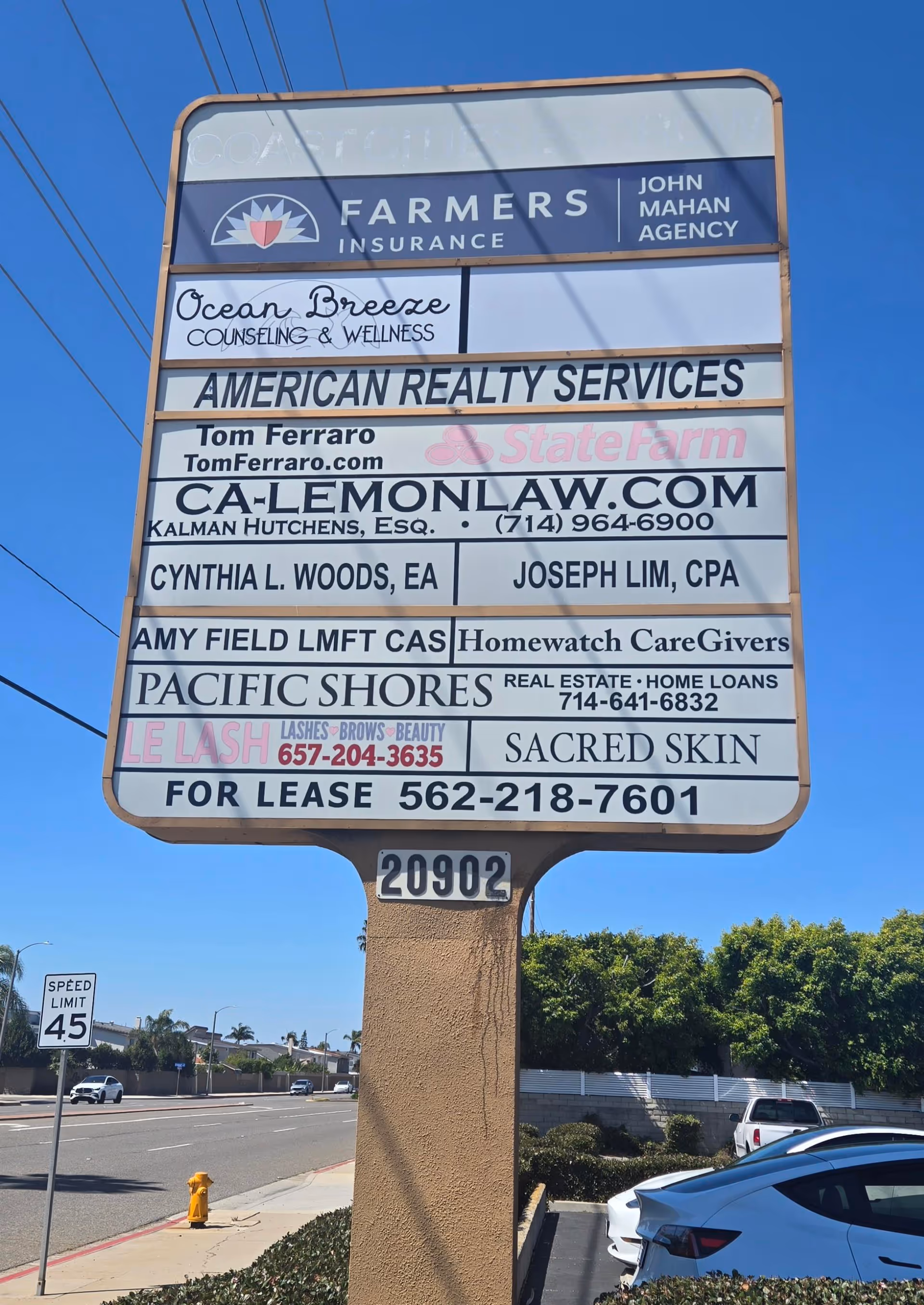 Tall outdoor signboard displaying multiple business ads, including Homewatch CareGivers, beside a street.