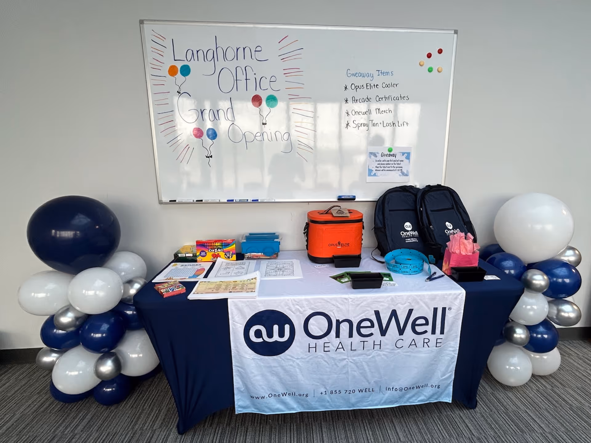 Registration table with OneWell Health Care banner and balloons inside a facility.