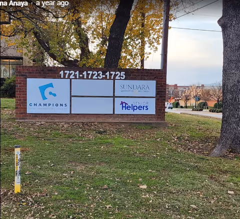 Exterior brick sign displaying Senior Helpers logos and other facility branding.