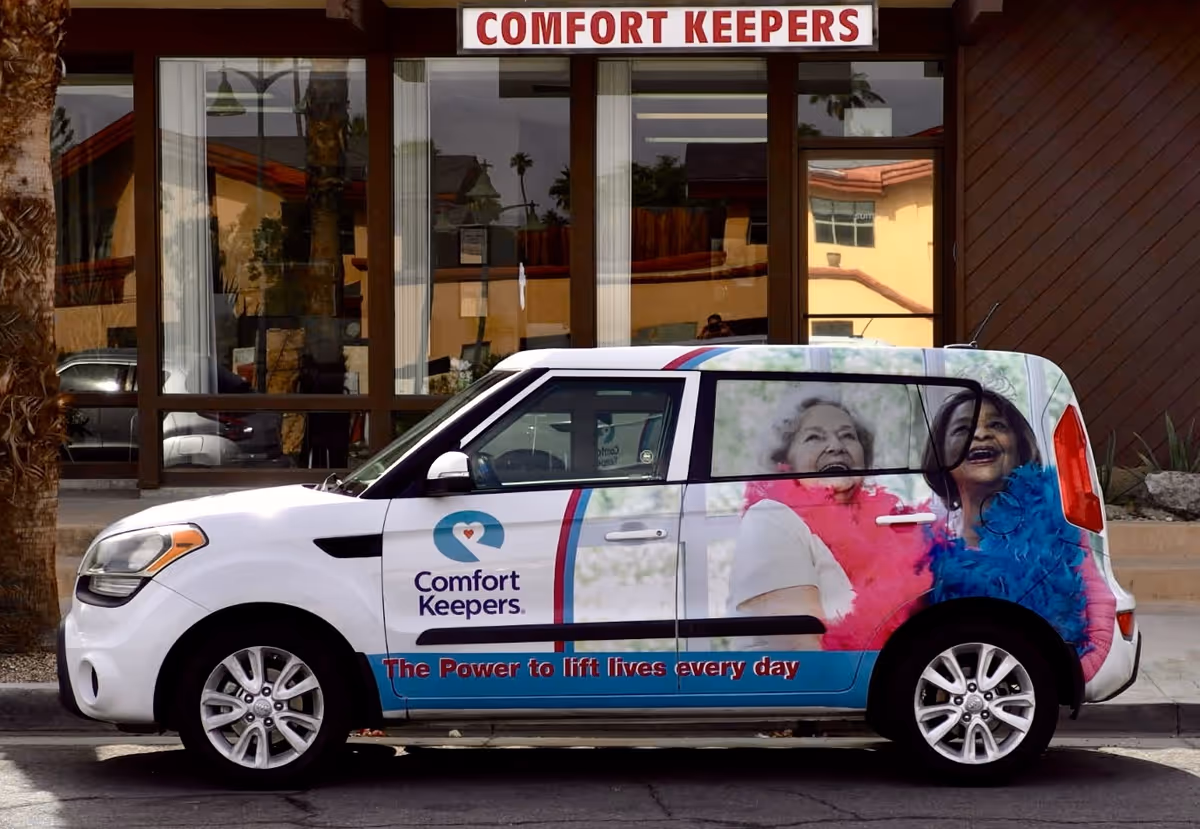 White Comfort Keepers van parked in front of a facility with large branding.
