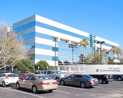 Blue-and-white multi-story senior care building with a parking lot in front.