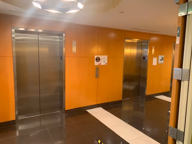 Interior hallway with wood-paneled walls and two silver elevator doors.