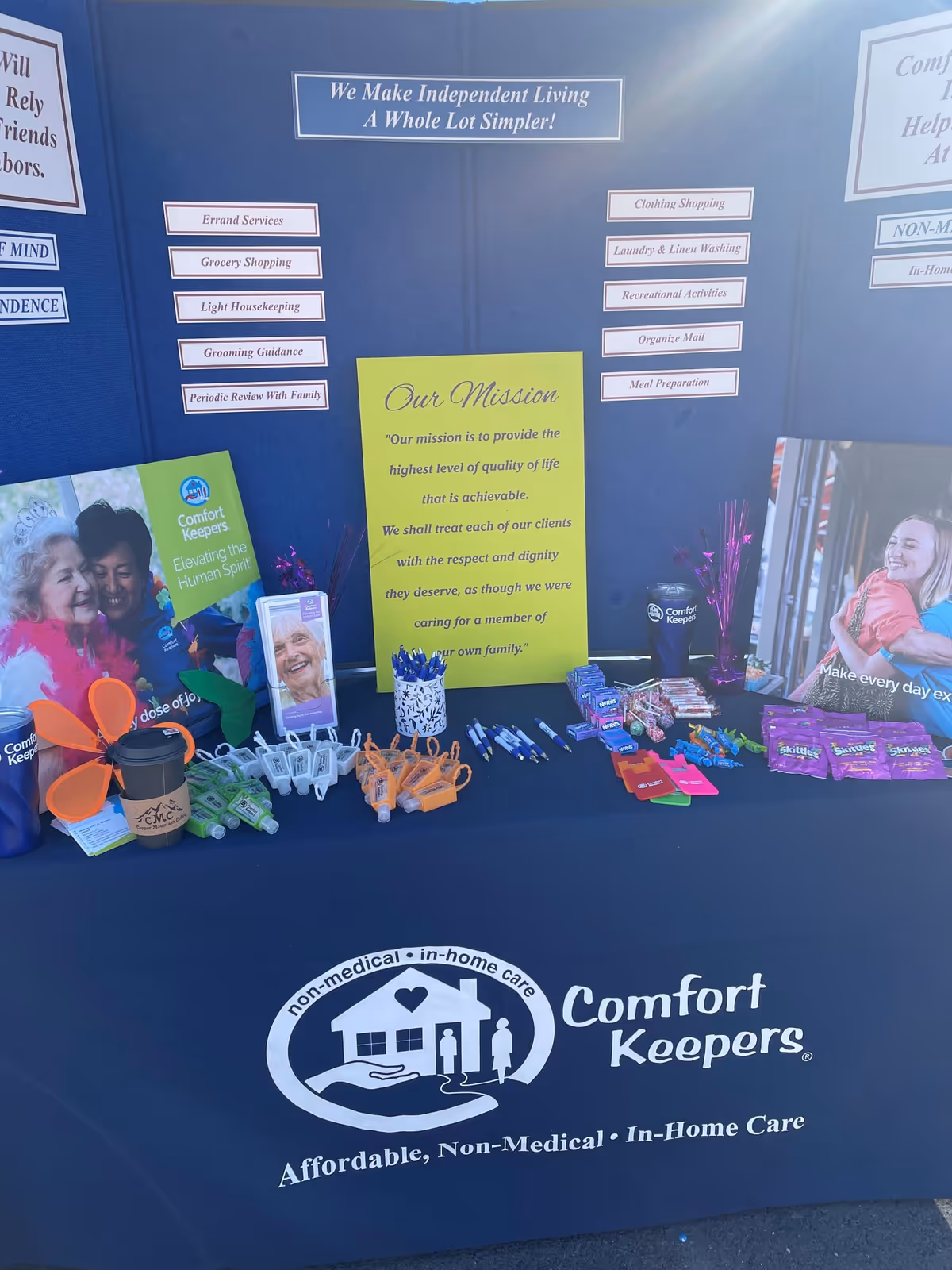 Promotional display for Comfort Keepers with brochures and promotional items on a blue backdrop.
