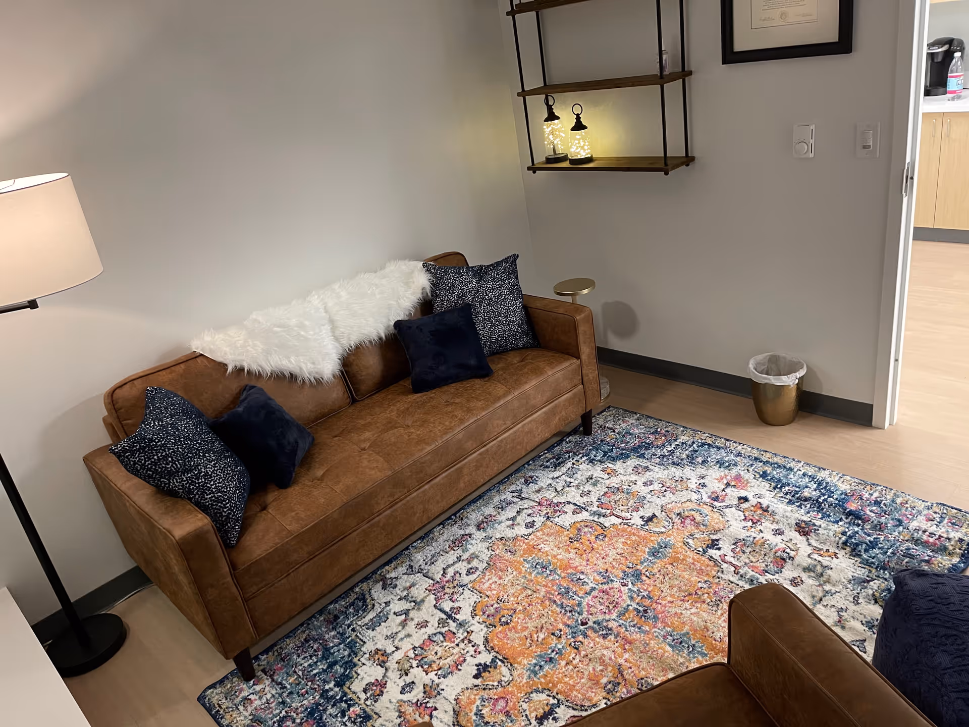 Brown leather sofa with navy cushions and a colorful rug in a modern living area.
