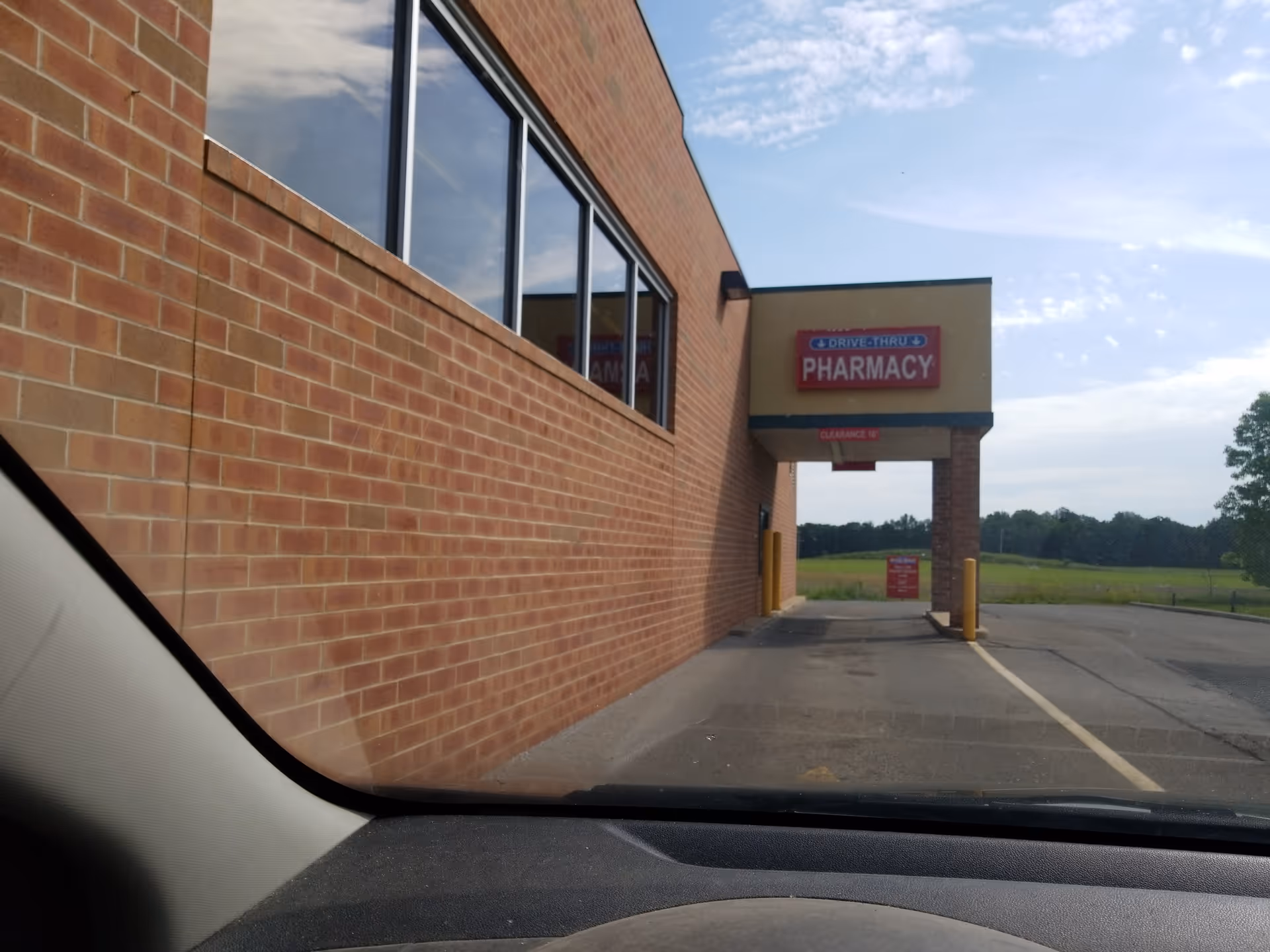 Photo from inside a car showing Discount Drug Mart exterior with a drive-thru pharmacy sign.