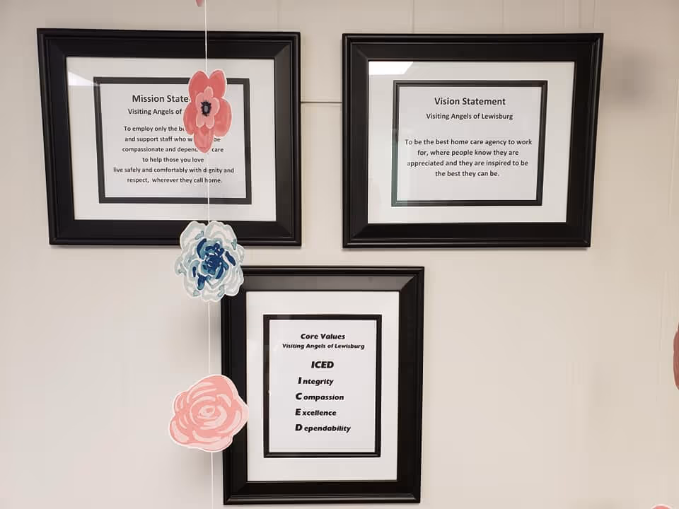 Wall displays framed mission, vision, and core values with hanging decorative flowers.