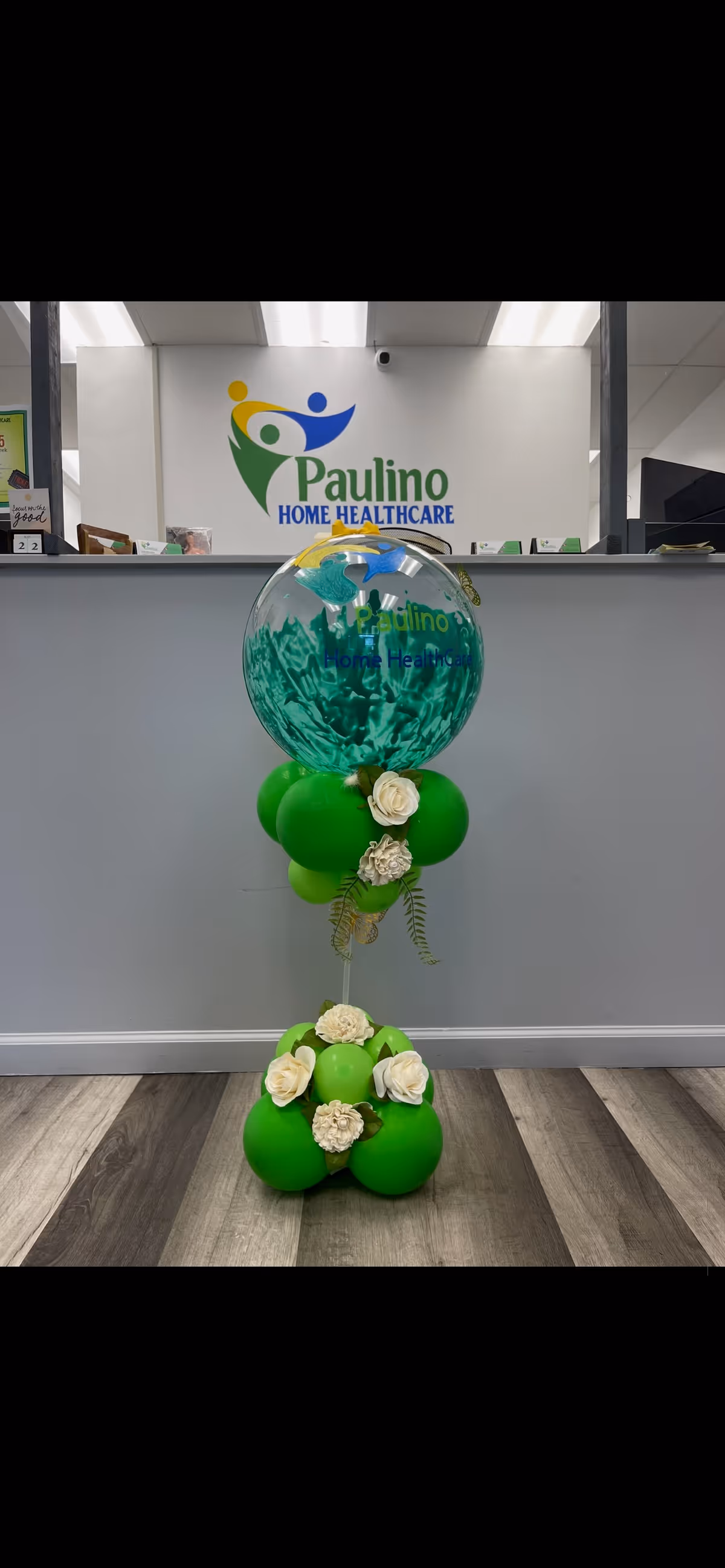 Reception area featuring Paulino Home Healthcare logo behind a green balloon centerpiece.
