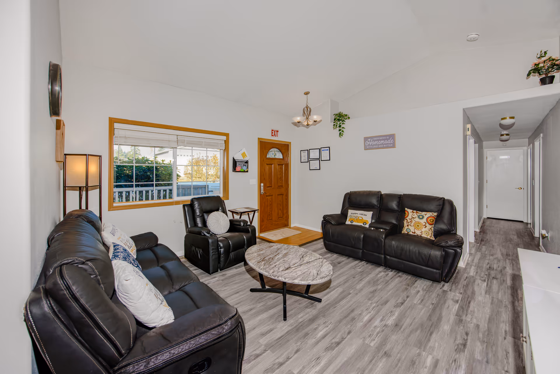 Cozy living room with black leather sofas, a marble coffee table, and entry hallway.