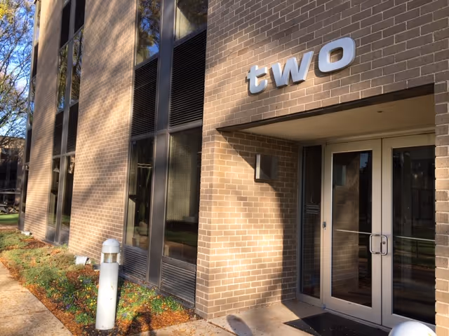 Brick building exterior with a glass door entrance and a large 'two' sign.