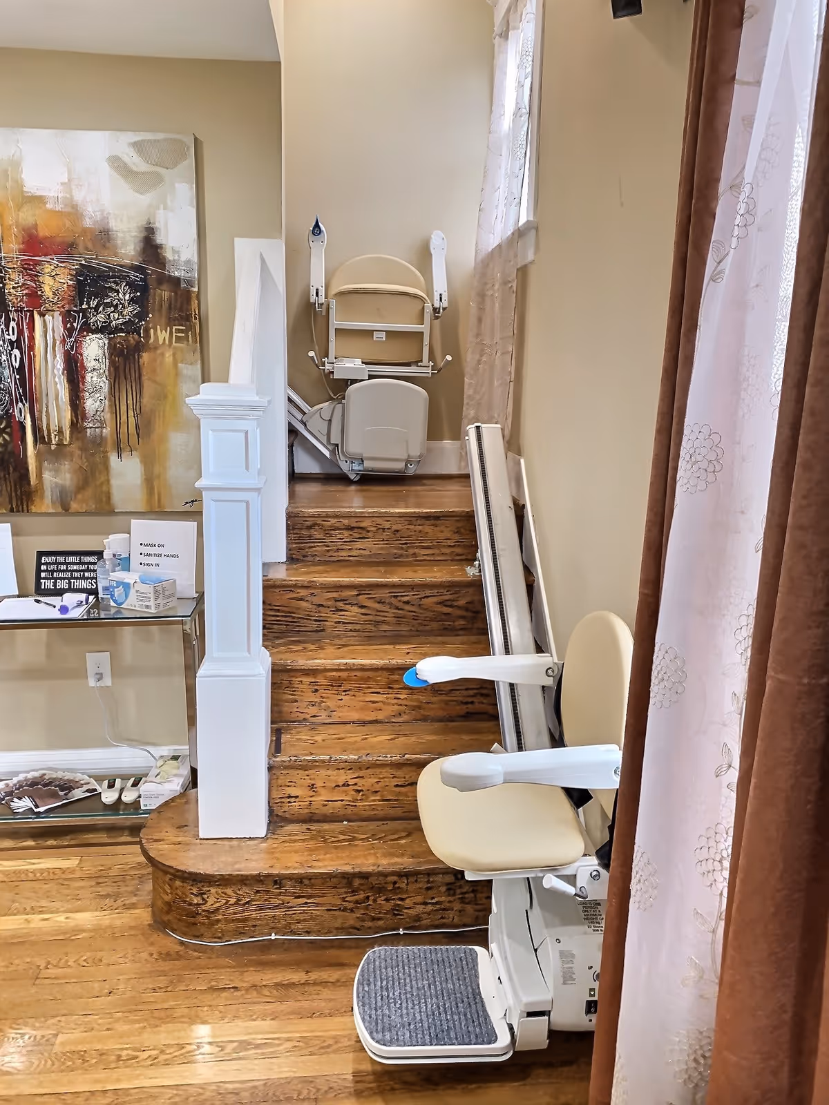 Indoor staircase with stairlift, beige seating, and mobility equipment in a residential space.