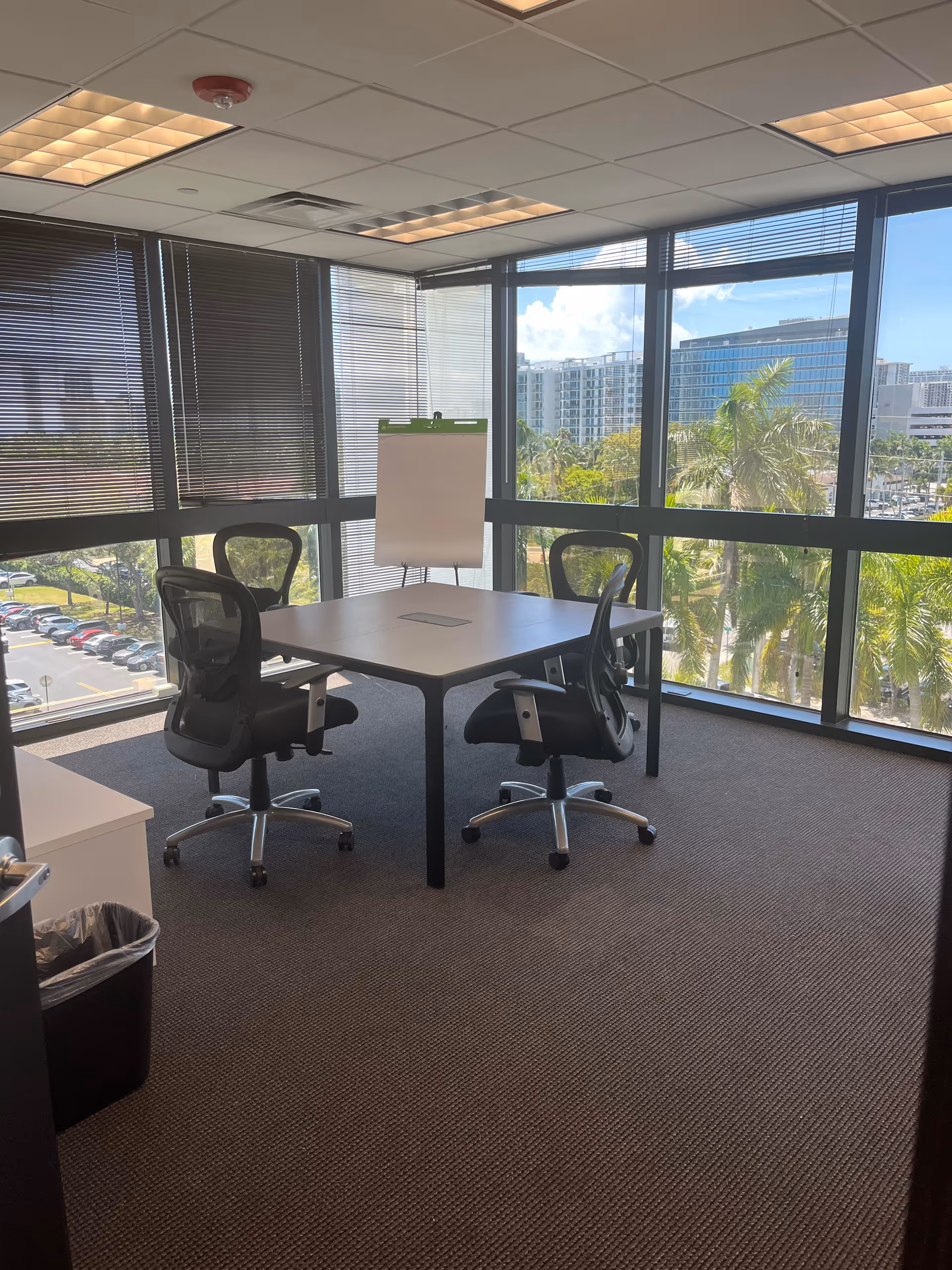 Interior office conference room with two chairs around a square table and large windows.