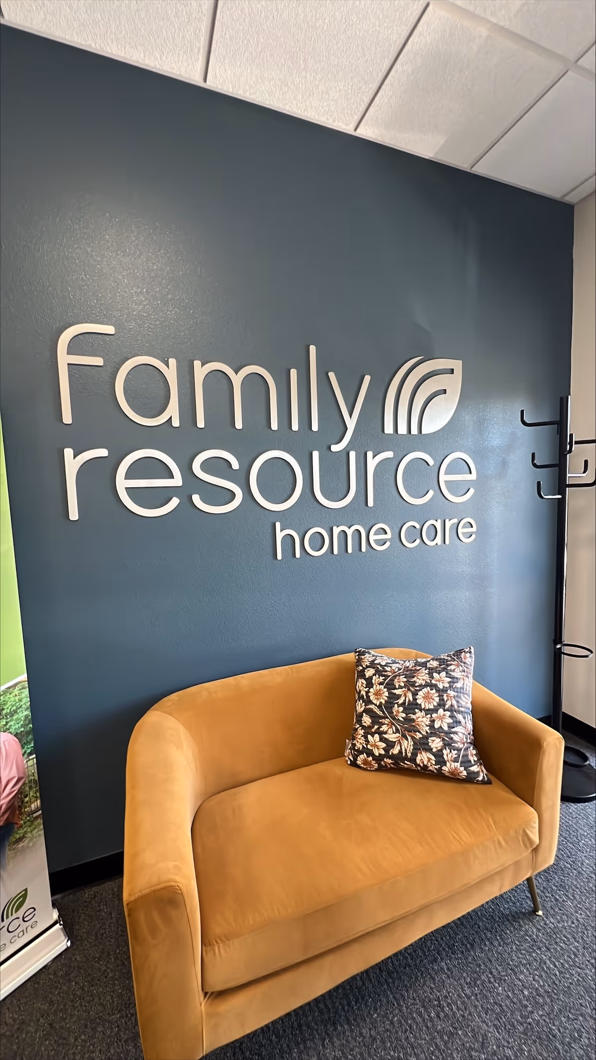 Blue interior wall with Family resource home care sign and a tan sofa with pillow.