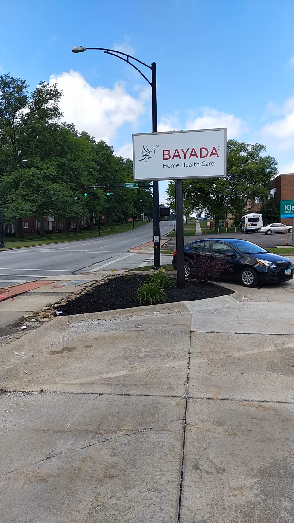 BAYADA Home Health Care sign on a street corner with trees.