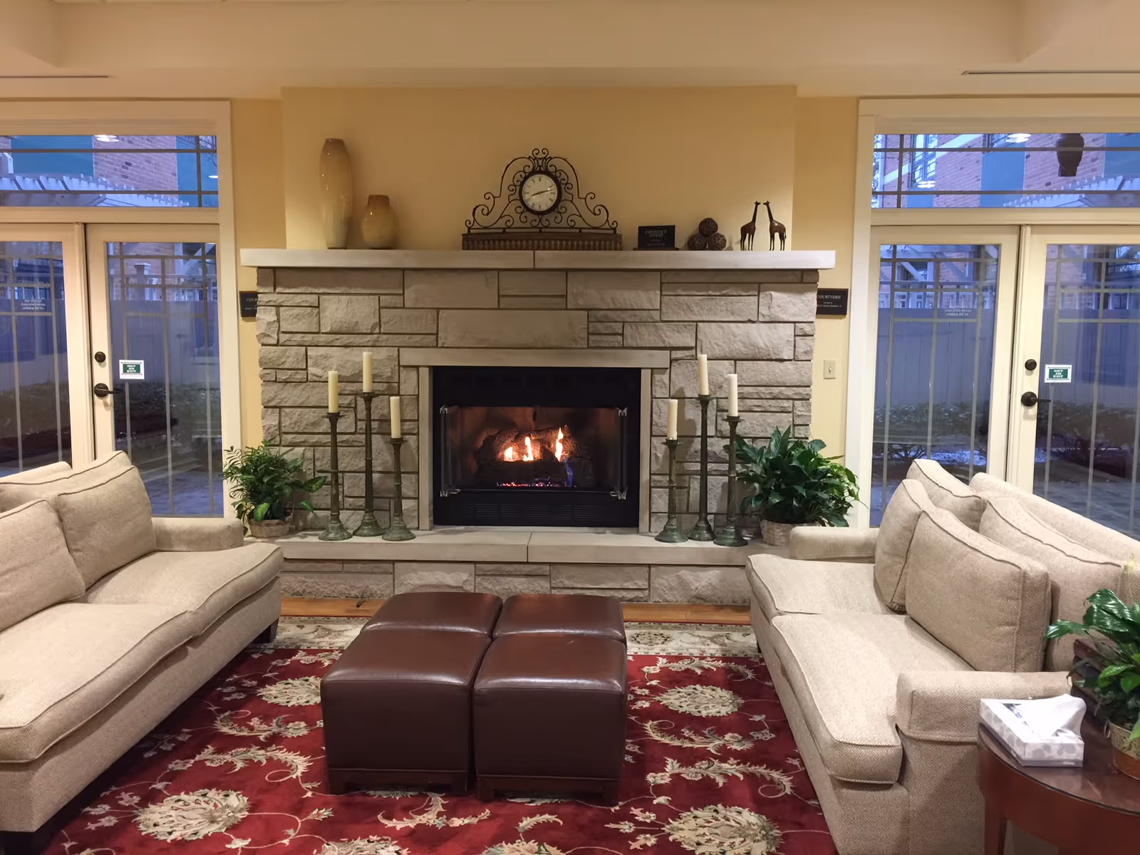 Cozy living room featuring a stone fireplace, beige sofas, and glass doors.