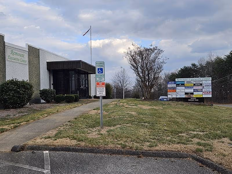 Exterior view of a senior living facility with a sidewalk, parking, and signage.