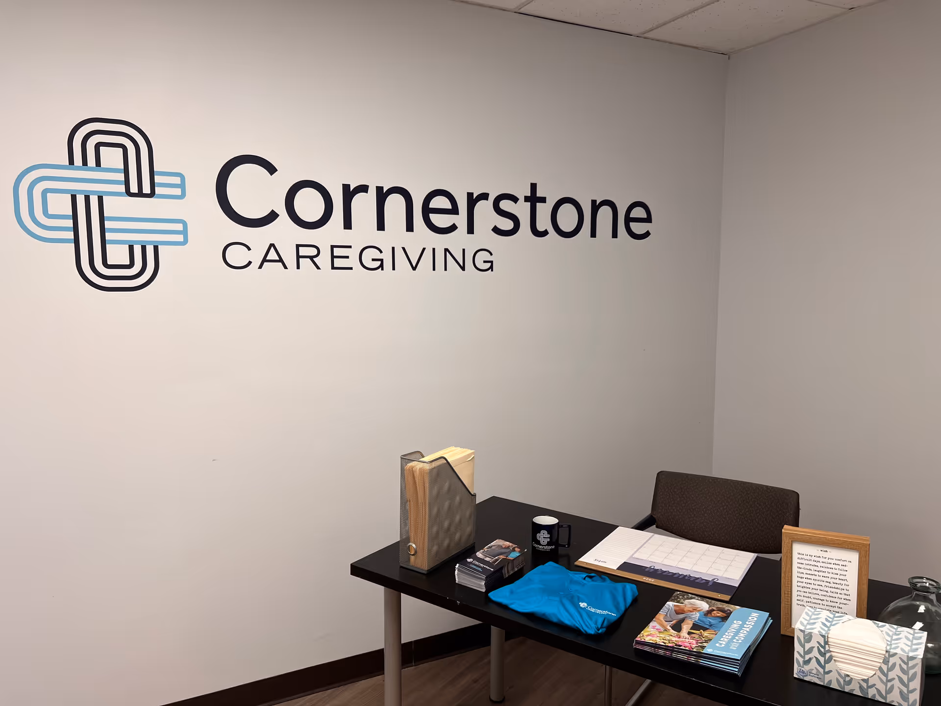 Interior reception area featuring Cornerstone Caregiving logo on the wall above a desk.