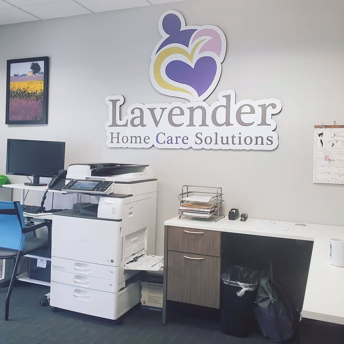 Interior office space featuring Lavender Home Care Solutions logo on the wall with copier and desk.