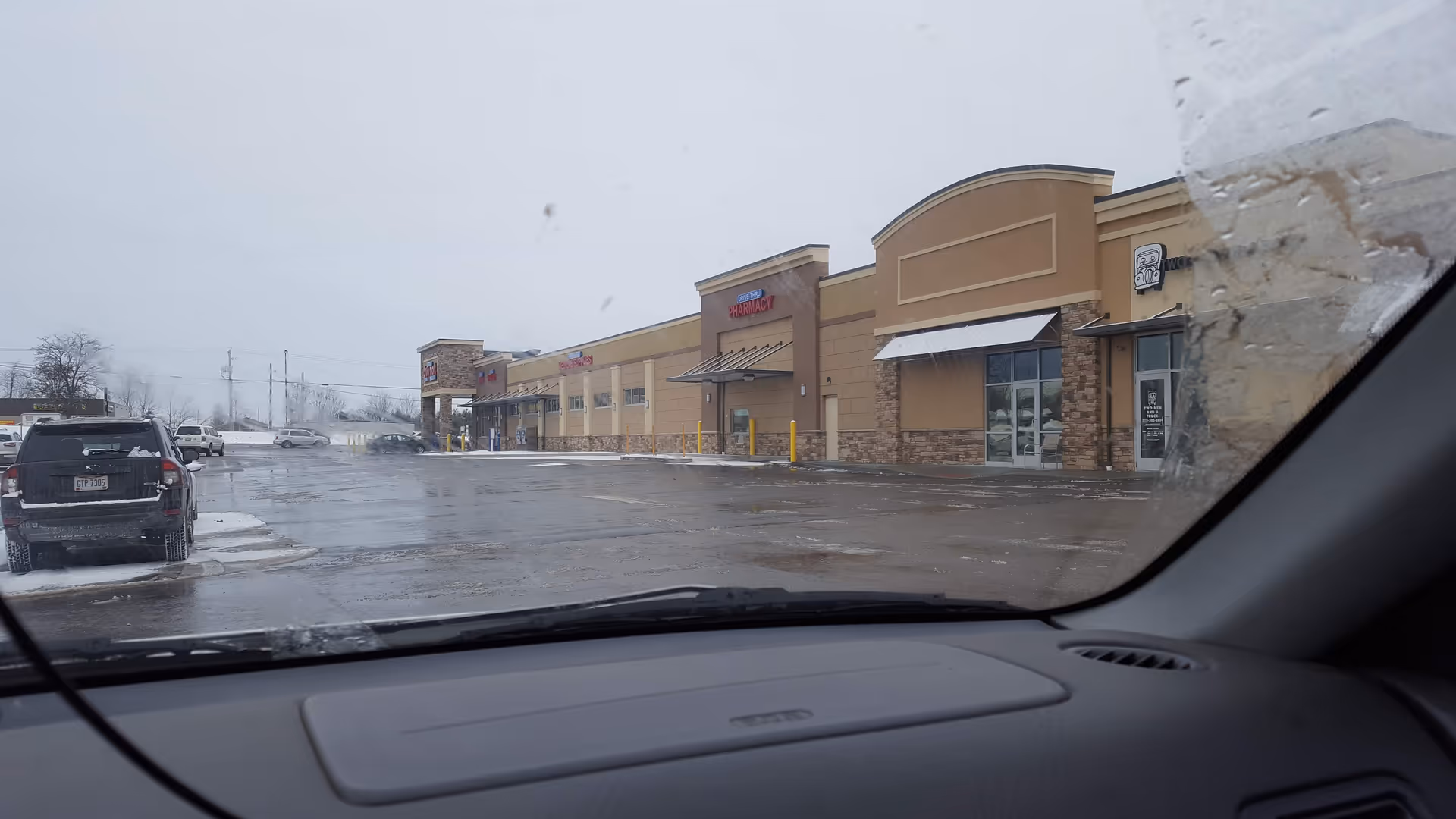 Exterior view of a Discount Drug Mart storefront in a strip mall, from a car windshield.