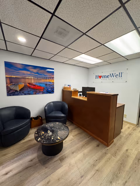Reception area with a wooden front desk, two black chairs, and a HomeWell sign.
