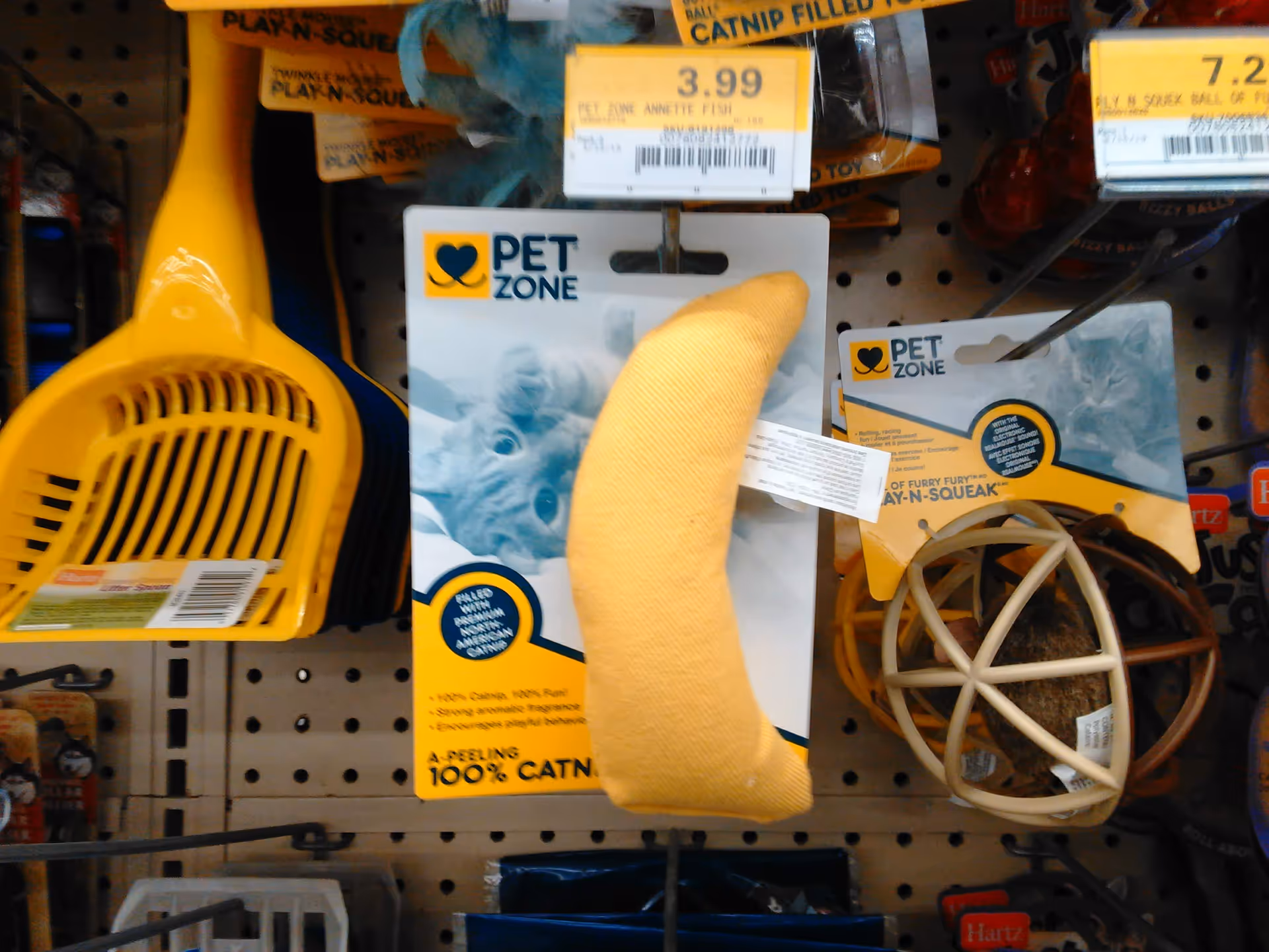 Shelf displaying Pet Zone pet toys, plus a yellow litter scoop in a store.