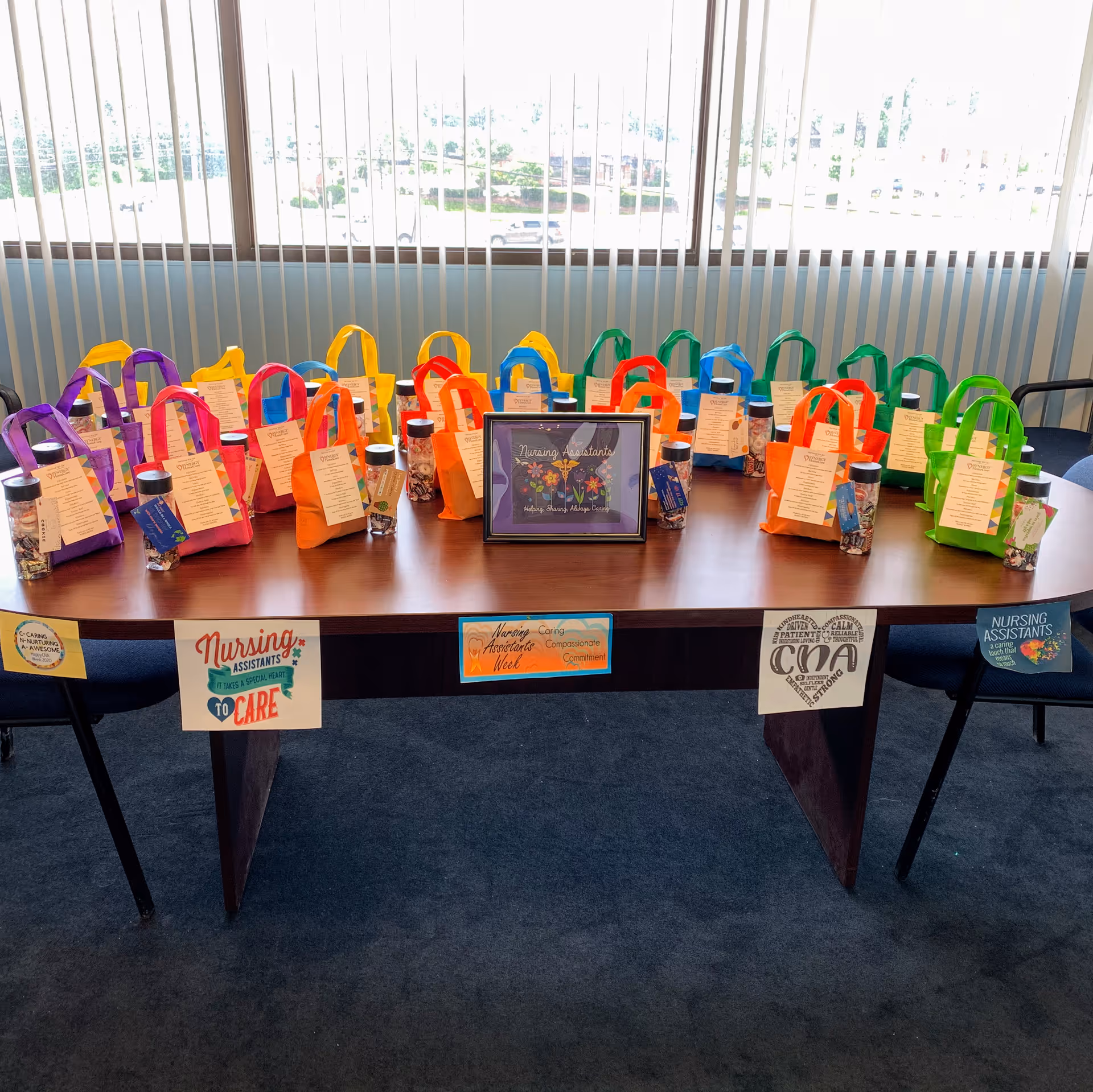 Colorful gift bags and a framed sign line a table in a bright interior.
