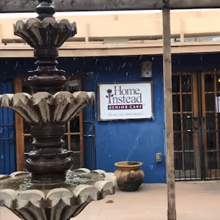 A decorative fountain outside a blue Home Instead Senior Care entrance.