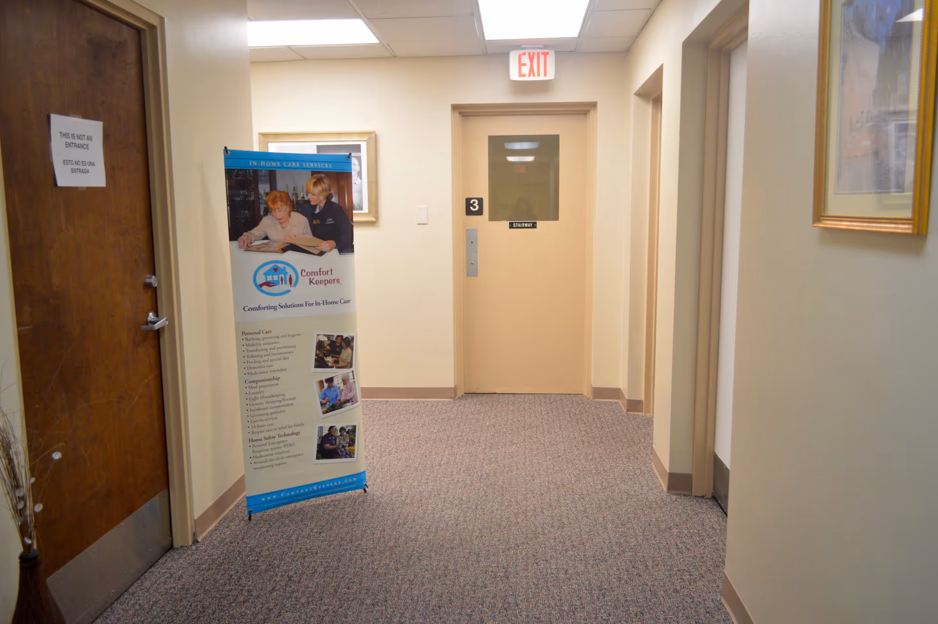 Hallway inside Comfort Keepers Home Care with an informational banner near a doorway.