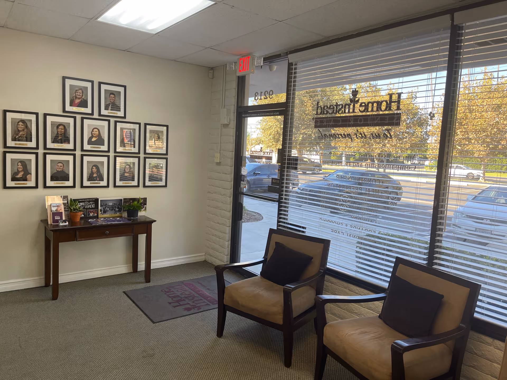 Interior waiting area with framed staff photos, a wooden console table, and two chairs.
