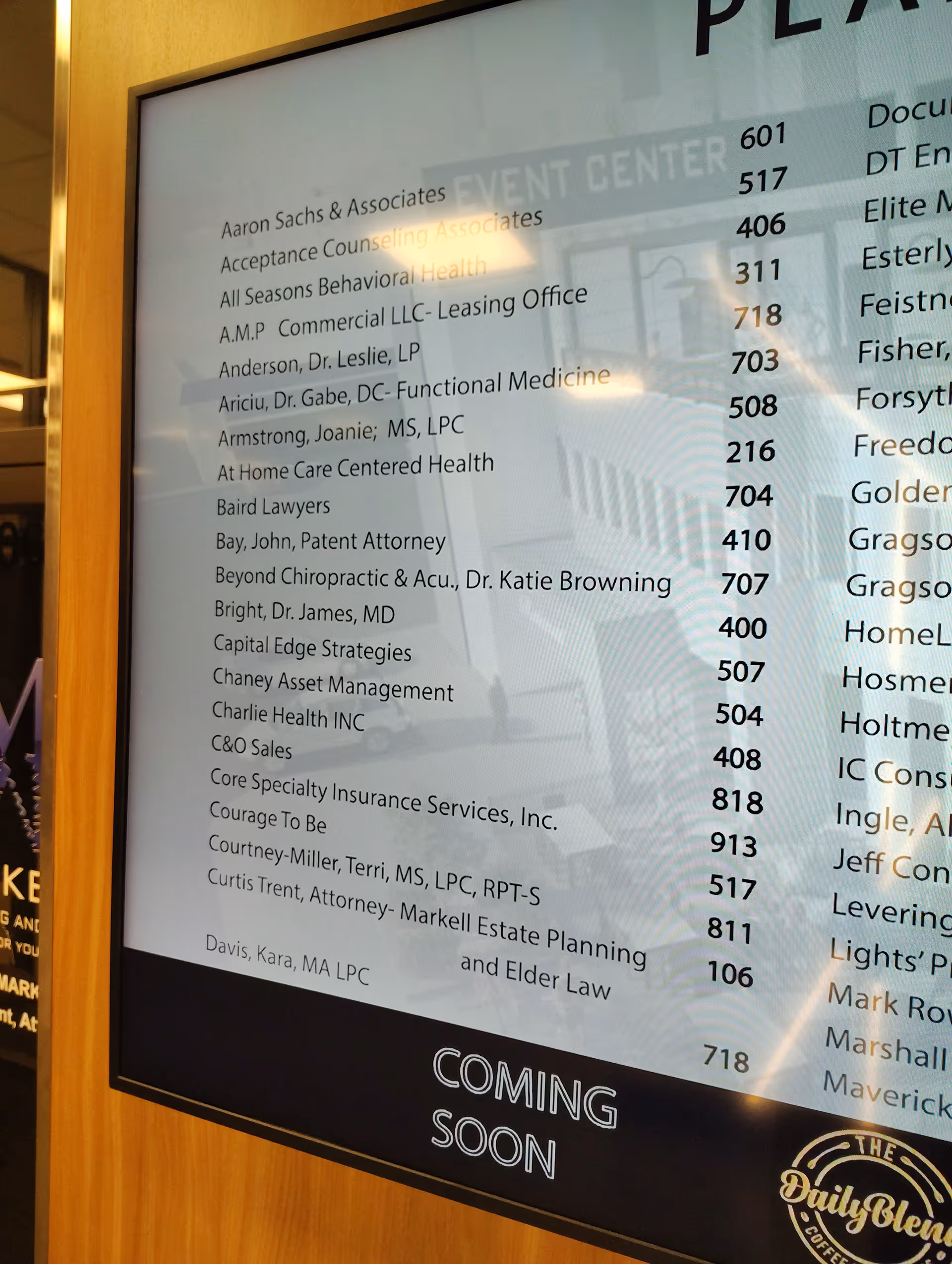 Indoor directory board in a lobby listing business names, including At Home Care, Coming Soon.