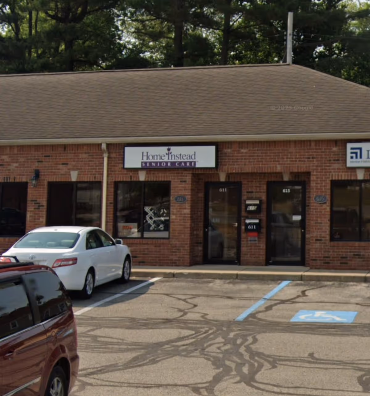 Brick building with Home Instead Senior Care sign and parked cars in front.
