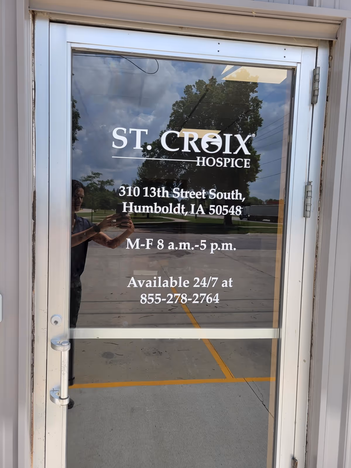 Glass door entry for St. Croix Hospice with address and surrounding reflections.