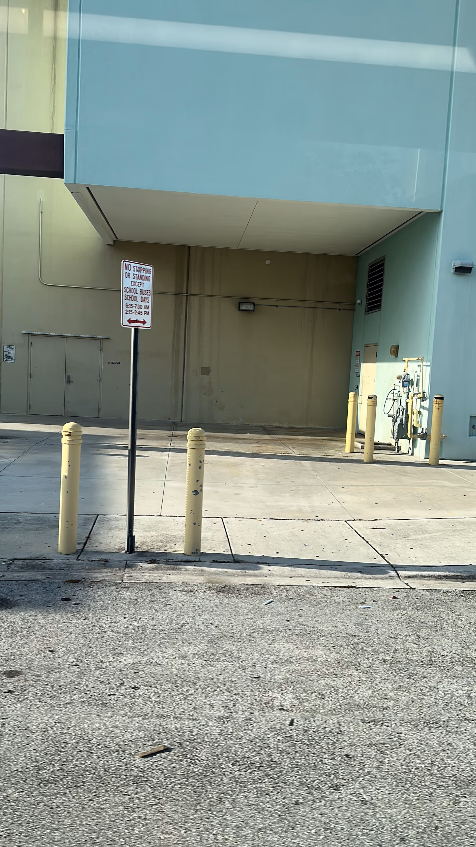 Exterior view of a building entrance with bollards, a sign, and a bike.