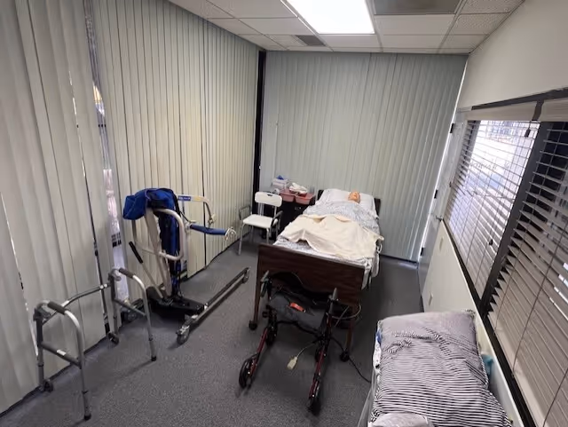 Narrow interior room with a hospital bed, wheelchair, walker, and medical equipment.