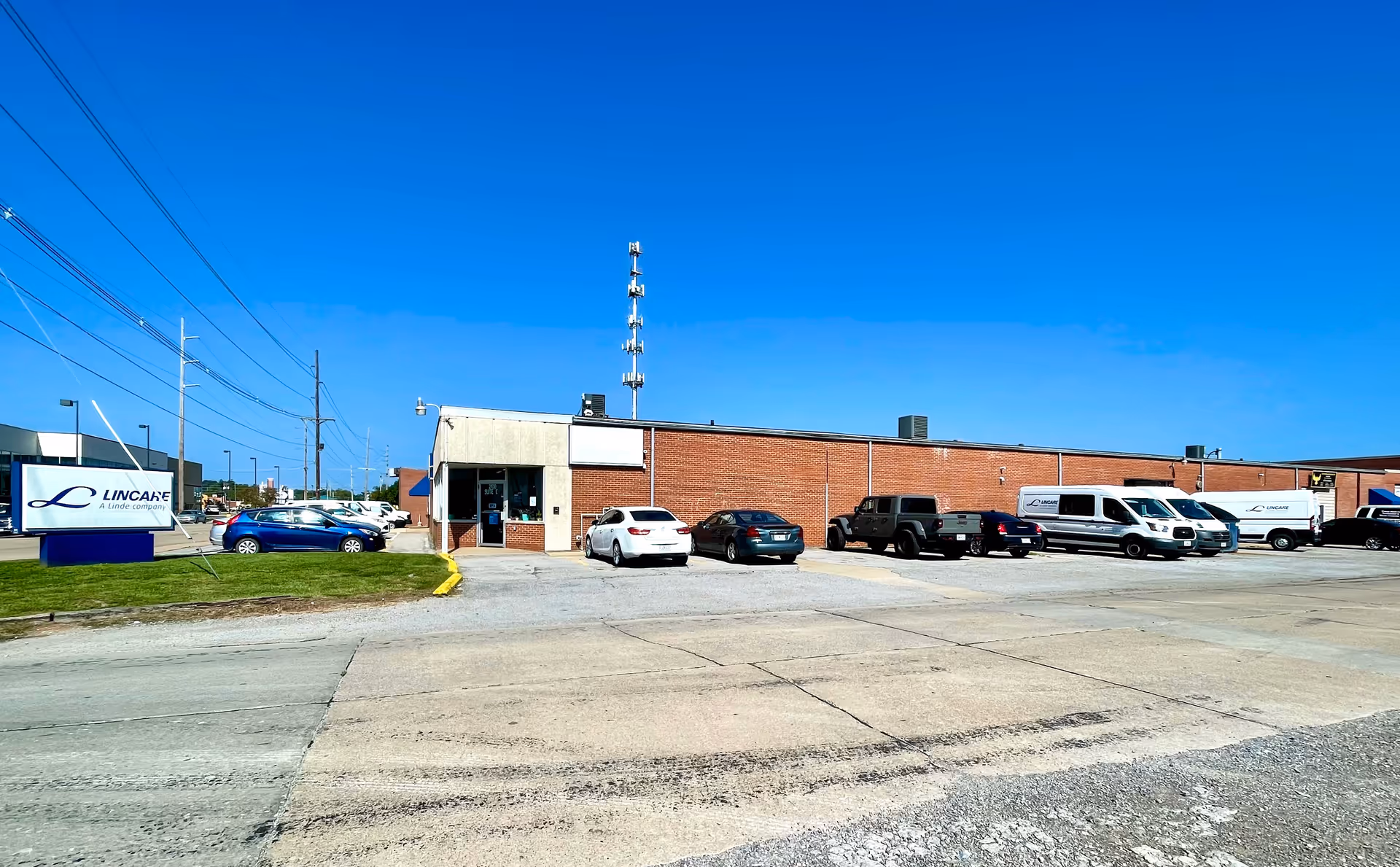 Exterior view of a Lincare facility building with a parking lot and several vehicles.