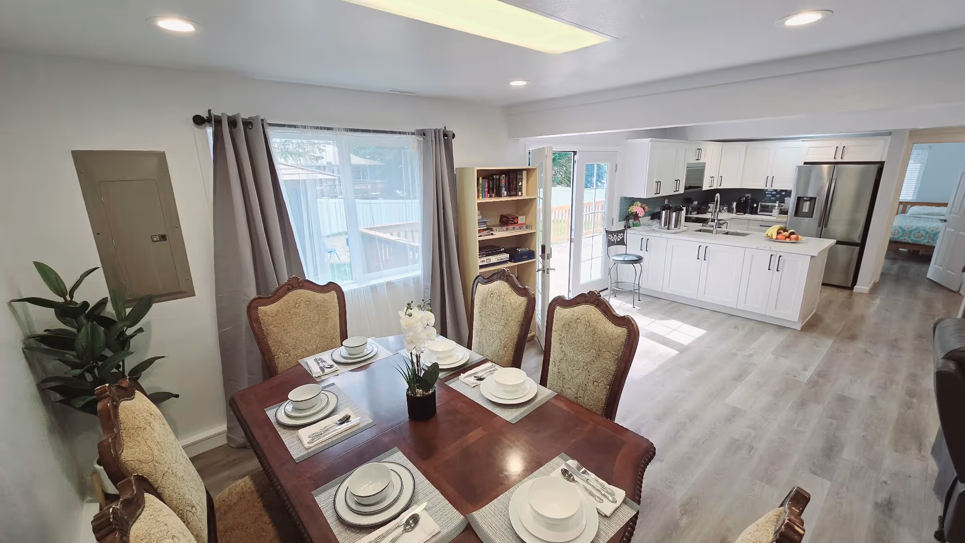 Spacious dining area with a table set for six and an open, bright kitchen.