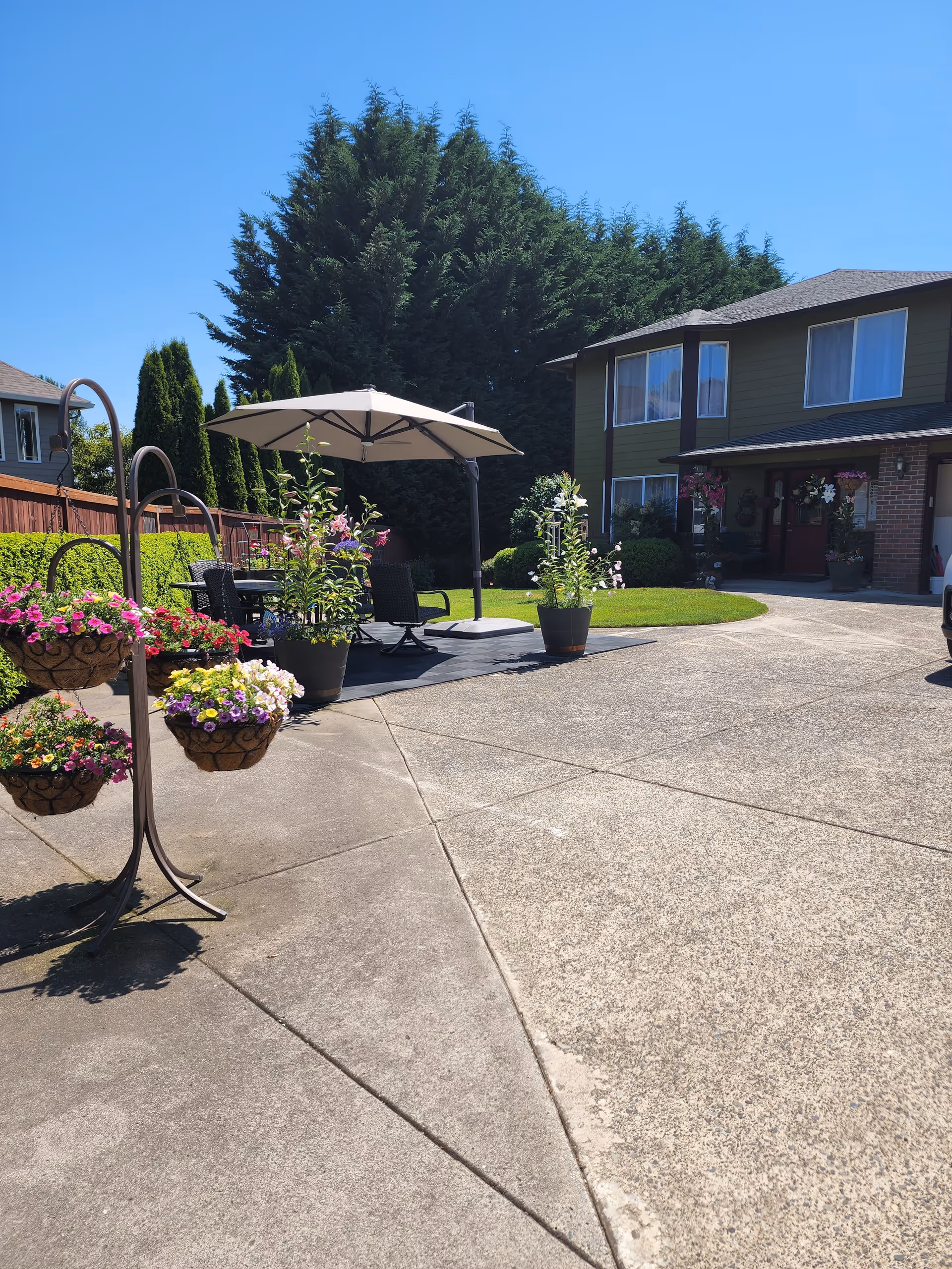 Outdoor patio area with umbrella, chairs, and potted flowers in front of a house.