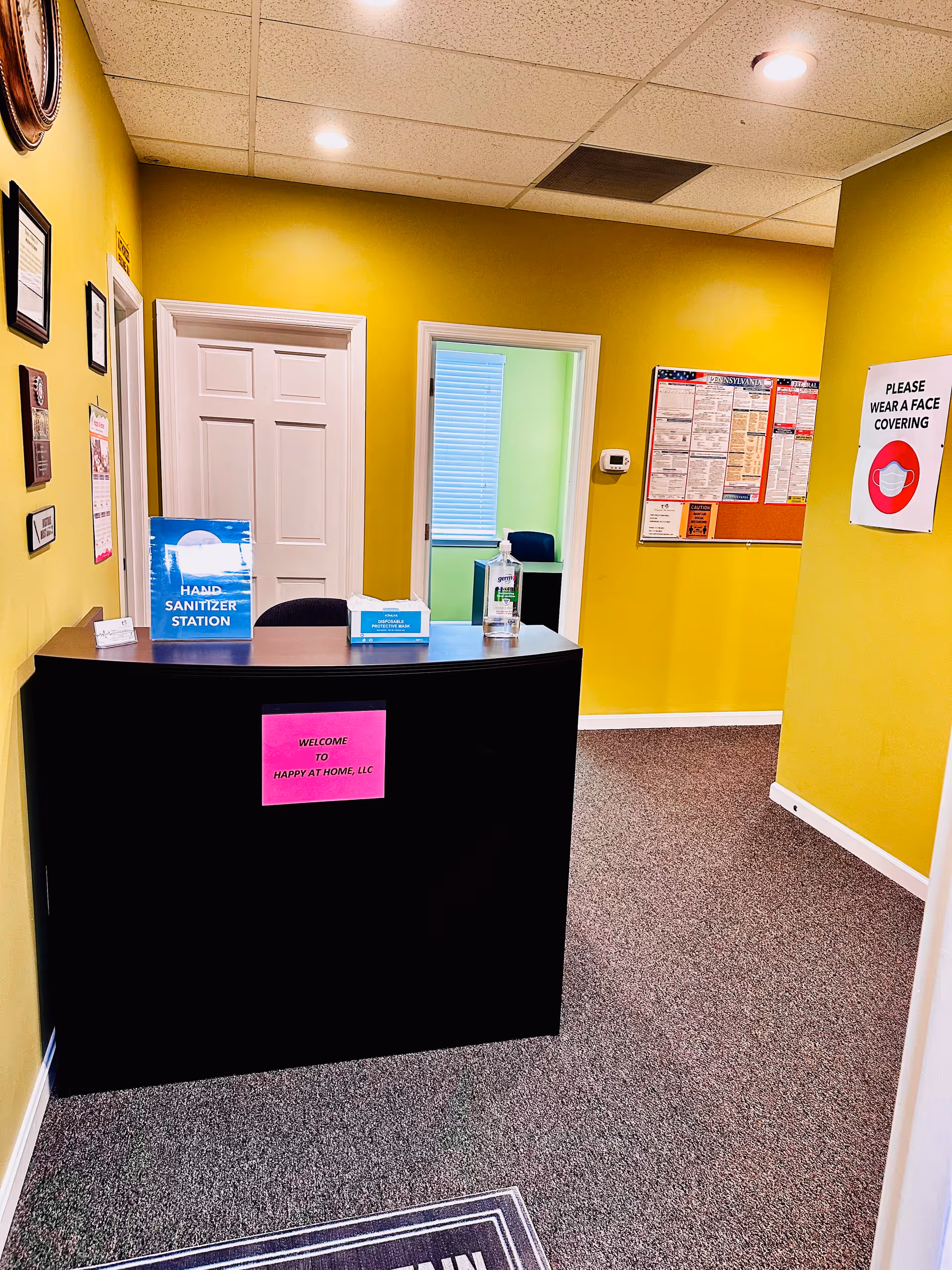 Reception desk in a bright yellow lobby with safety signage and a welcome sign.