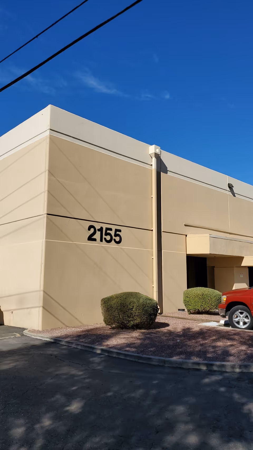 Beige building exterior with the address 2155 and a red pickup truck.