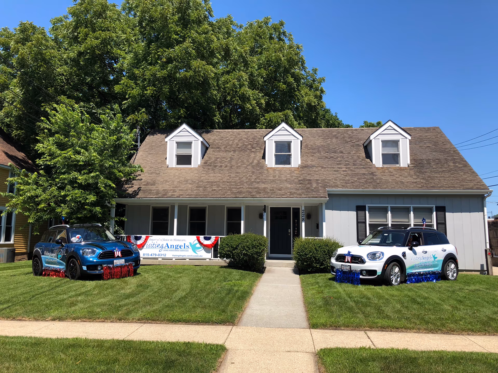 Front view of Visiting Angels Senior Home Care building with two cars parked on the lawn.